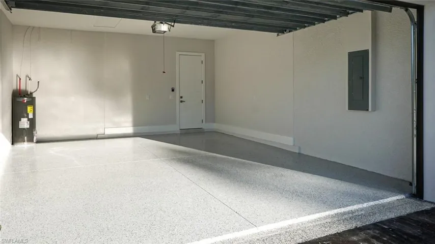 Garage featuring a garage door opener, electric panel, and electric water heater