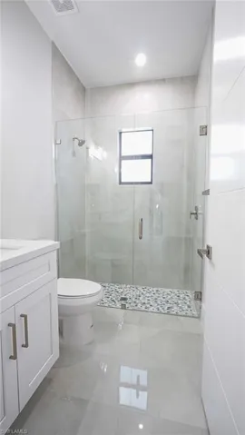 Full bath featuring a stall shower, vanity, and toilet