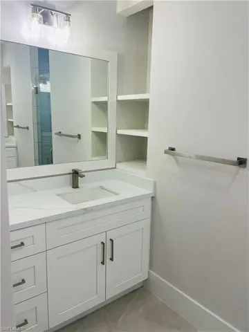 Full bathroom featuring a stall shower, vanity, and baseboards