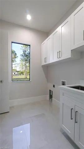 Laundry area with hookup for a washing machine, recessed lighting, baseboards, cabinet space, and electric dryer hookup