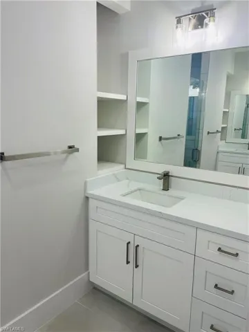 Full bath featuring a stall shower, baseboards, and vanity