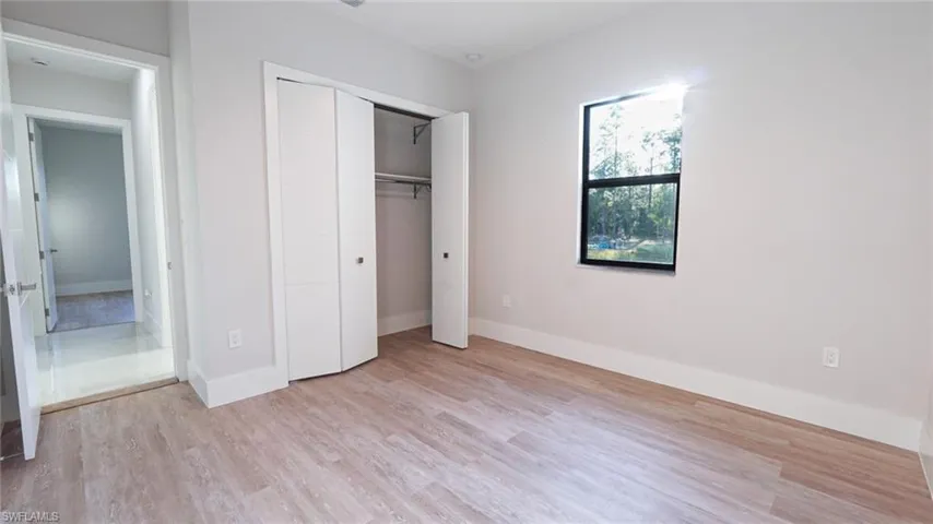 Unfurnished bedroom featuring a closet, baseboards, and light wood finished floors