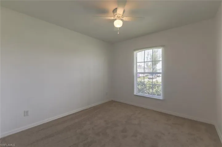 Carpeted spare room featuring ceiling fan