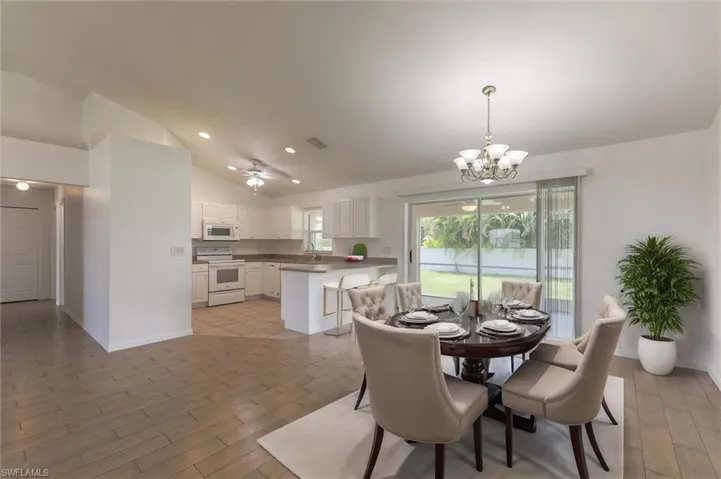 Dining room featuring sink, vaulted ceiling, ceiling fan with notable chandelier, and light hardwood / wood-style floors