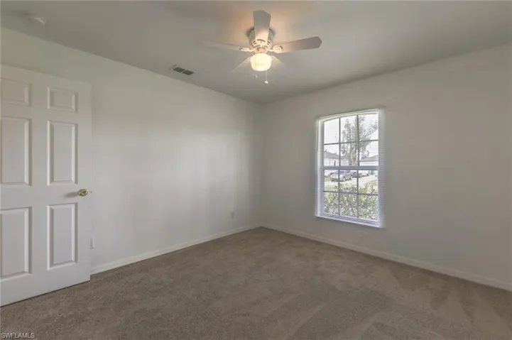 Carpeted spare room with ceiling fan