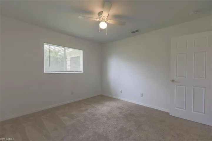 Empty room featuring light colored carpet and ceiling fan