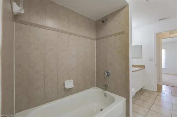 Full bathroom featuring tile patterned flooring, toilet, tiled shower / bath, and vanity