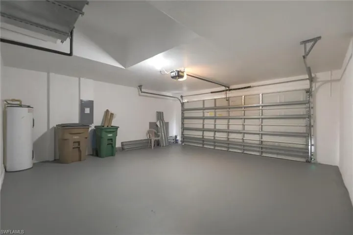 Garage with a garage door opener, electric water heater, and electric panel