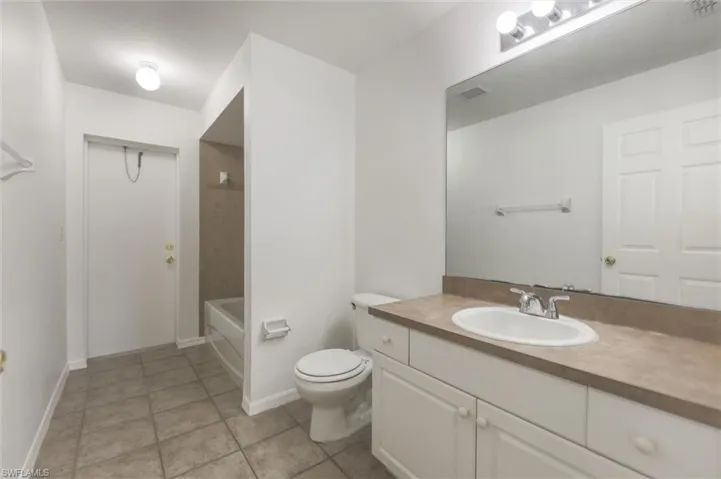 Full bathroom featuring toilet, vanity, shower / bath combination, and tile patterned floors