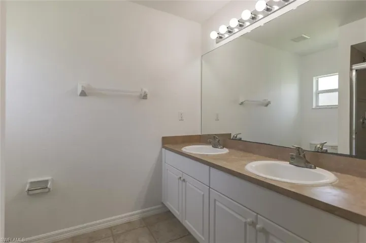 Bathroom with dual vanity and tile patterned flooring