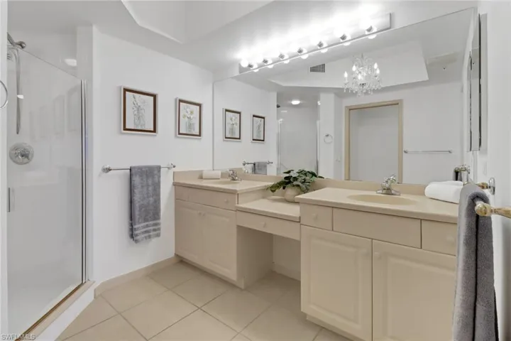 Bathroom featuring an enclosed shower, vanity, dual sinks and tile patterned floors