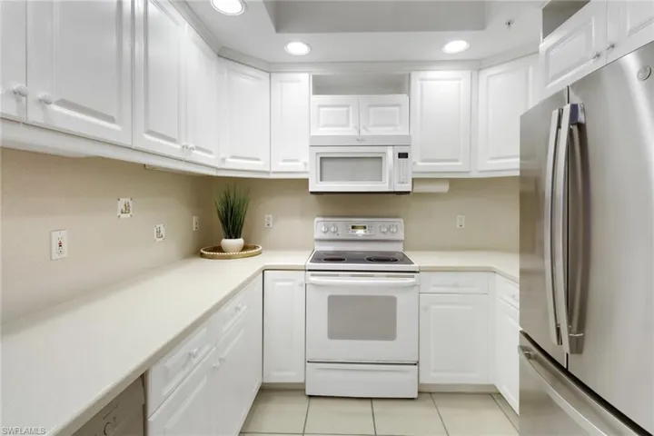 Kitchen featuring white appliances, white cabinetry with under-cabinet lighting, and light tile patterned flooring