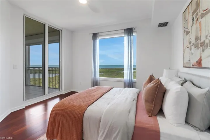 Bedroom with hardwood floors and access to screened-in lanai with views of the gulf.