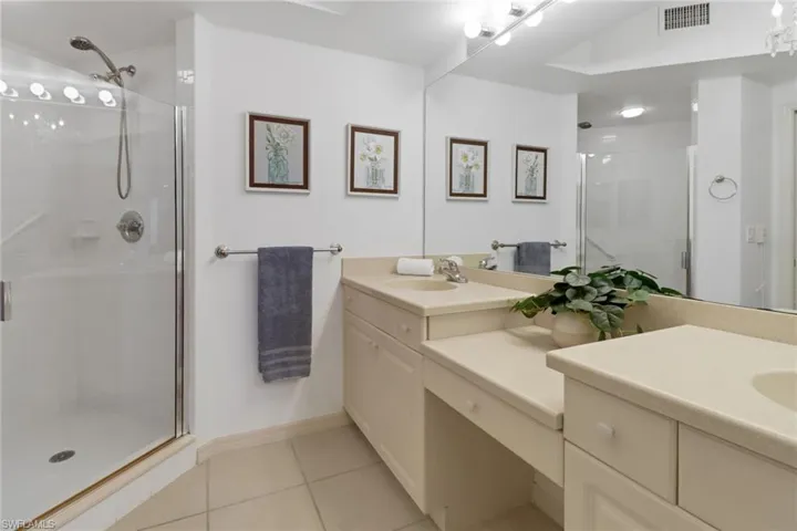 Bathroom with tile patterned floors, vanity, dual sinks and an enclosed shower