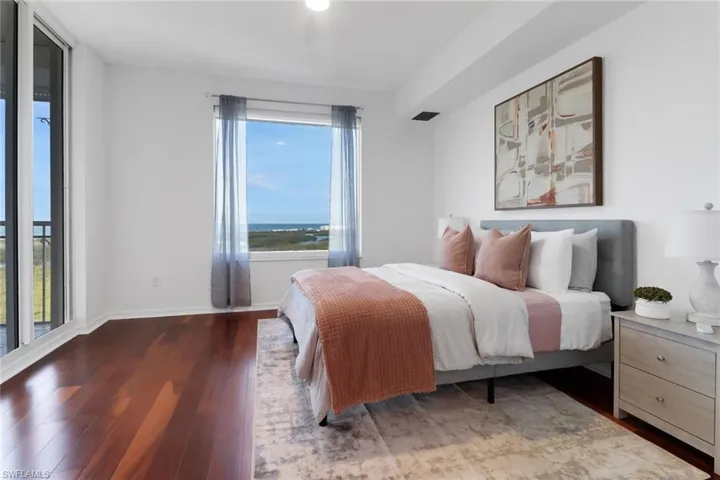 Bedroom featuring hardwood floors, access to the screened-in lanai with views of the gulf.