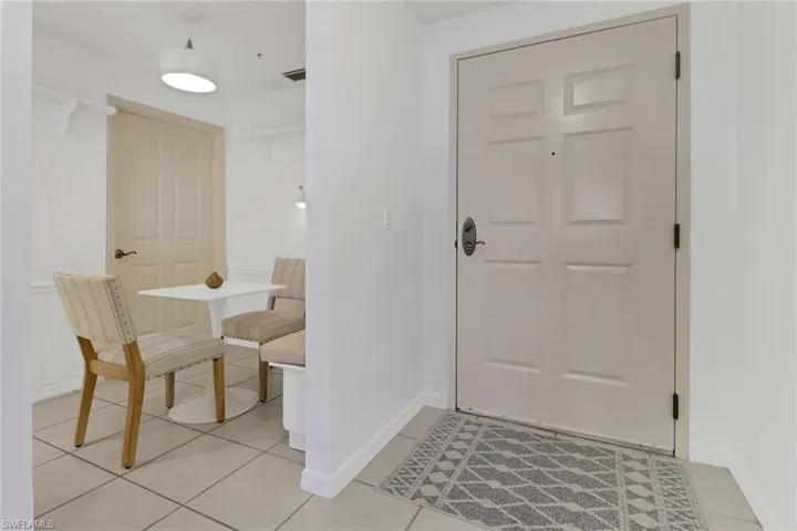 View of tiled foyer entrance with breakfast nook and bench; door leads to laundry room