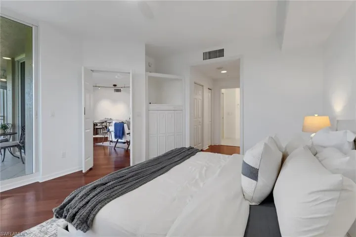Bedroom featuring hardwood flooring, king-size bed and access to the screened-in lanai with views of the gulf; master to the right with closets on both sides; TV can fit in built-in cabinetry.