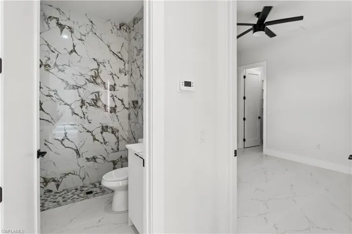 Unfurnished dining area with plenty of natural light, wine cooler, suspended lighting, a tray ceiling, and light marble finish floors