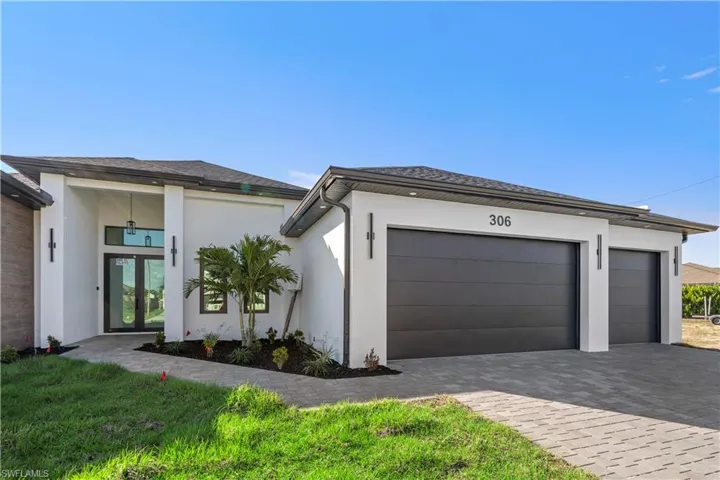 View of side of home featuring decorative driveway, stucco siding, an attached garage, french doors, and roof with shingles