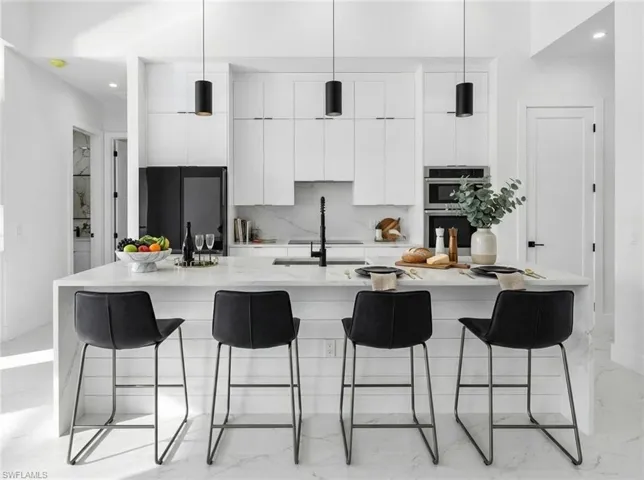 Kitchen with modern cabinets, light stone counters, white cabinetry, a large island, and stainless steel double oven