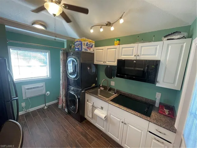 Laundry area with stacked washer / drying machine, a ceiling fan, and wood tiled floors