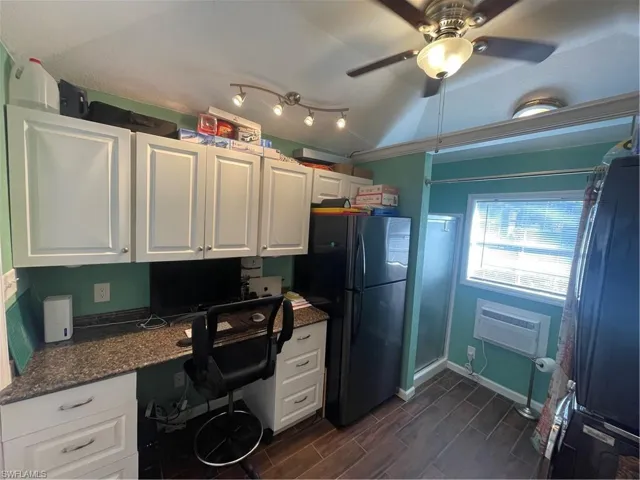 Home office with a ceiling fan, wood tiled floors, built in study area, and vaulted ceiling