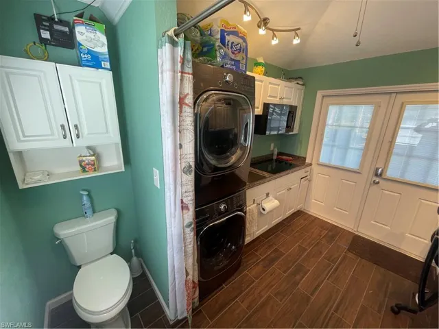 Bathroom with a shower with curtain, stacked washer and dryer, vaulted ceiling, and wood tiled floors