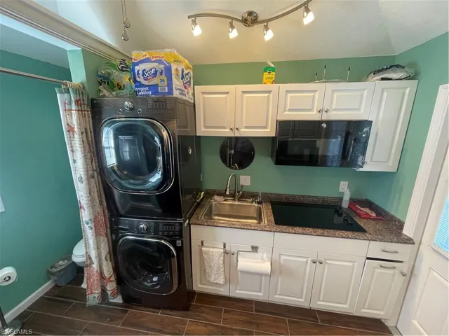 Laundry area with stacked washer / dryer and wood tiled floors