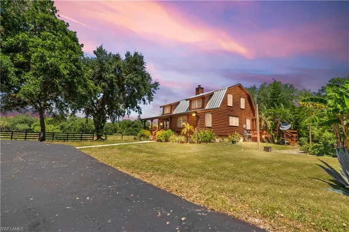 View of side of property with fence, a gambrel roof, a lawn, and metal roof