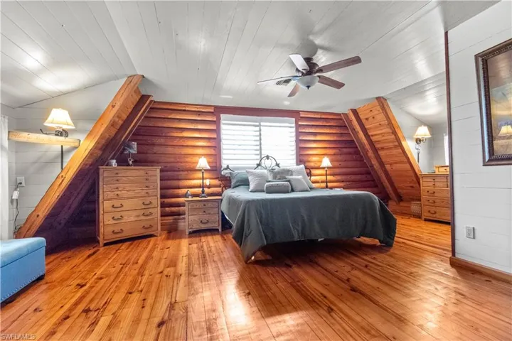 Bedroom featuring rustic walls, light wood-style floors, a ceiling fan, and wooden ceiling