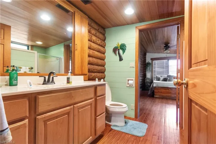 Ensuite bathroom featuring a shower stall, wooden ceiling, log walls, and a healthy amount of sunlight