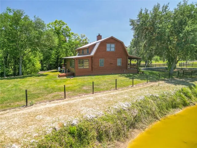 View of side of property with a lawn, a gambrel roof, fence, and a chimney