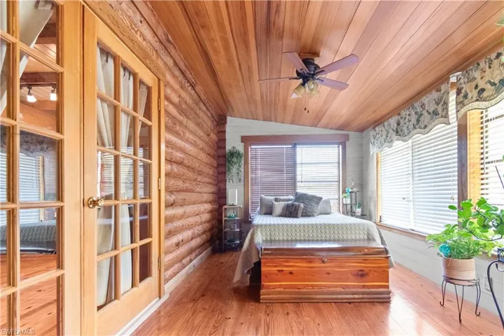 Bedroom featuring wood ceiling, hardwood / wood-style flooring, rustic walls, and lofted ceiling
