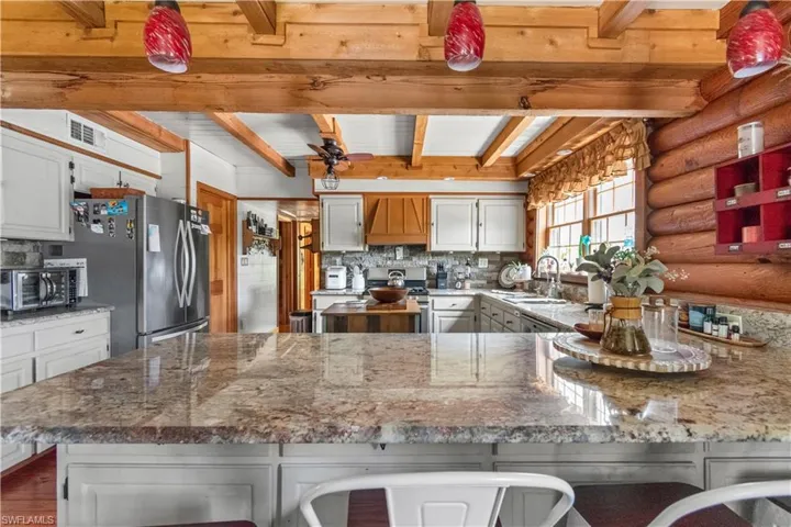 Kitchen featuring visible vents, a sink, beamed ceiling, tasteful backsplash, and appliances with stainless steel finishes
