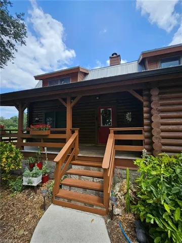 Property entrance featuring metal roof, log exterior, a chimney, and covered porch