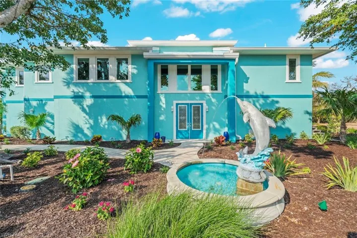 Exterior front with water feature. Home is elevated with an interior staircase to main level. Lower level offers an abundance of storage space.