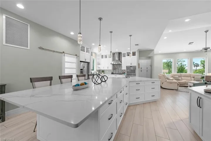 Chefs kitchen with white cabinets, stainless steel appliances, and expansive island
