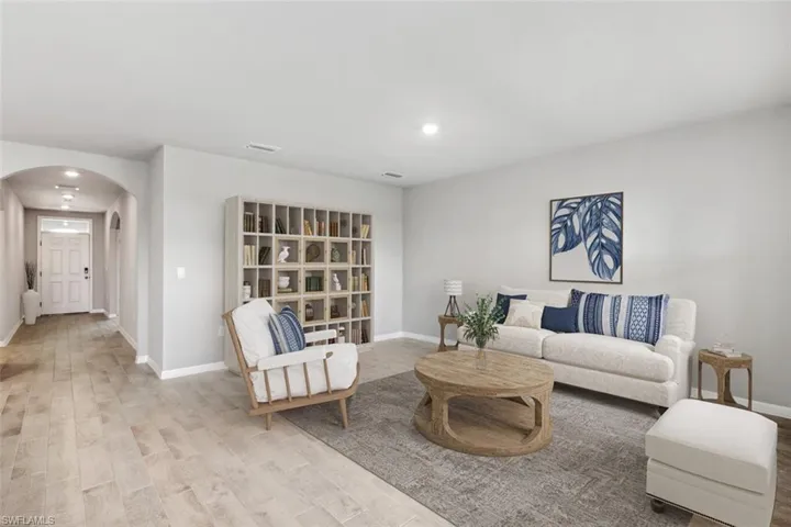 Virtually Staged- Living room with arched walkways, recessed lighting, and wood finished floors
