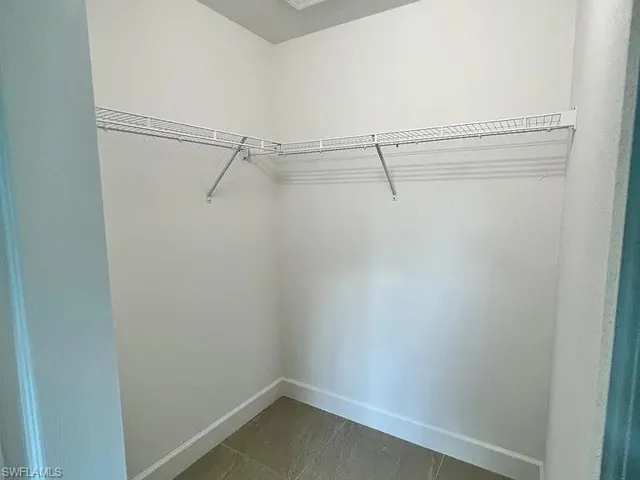 Walk-in storage space featuring neutral tile flooring and white wire shelving
