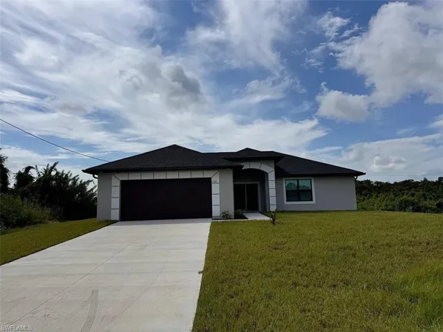Single-story residence featuring a stucco exterior, hipped roof, arched entryway, and concrete driveway