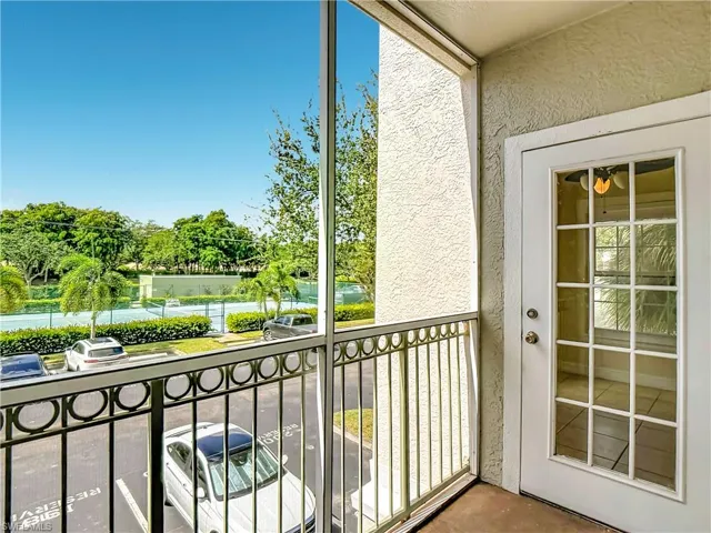 Screened balcony featuring metal railing, textured stucco wall, and a multi-pane glass entry door
