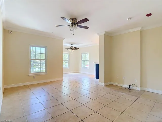 Neutral-toned tile flooring, dual ceiling fans, crown molding, and multiple multi-pane windows