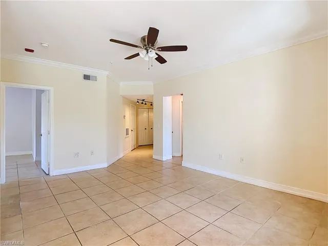 Interior space featuring neutral-toned tile flooring, crown molding, and a central ceiling fan with integrated lighting