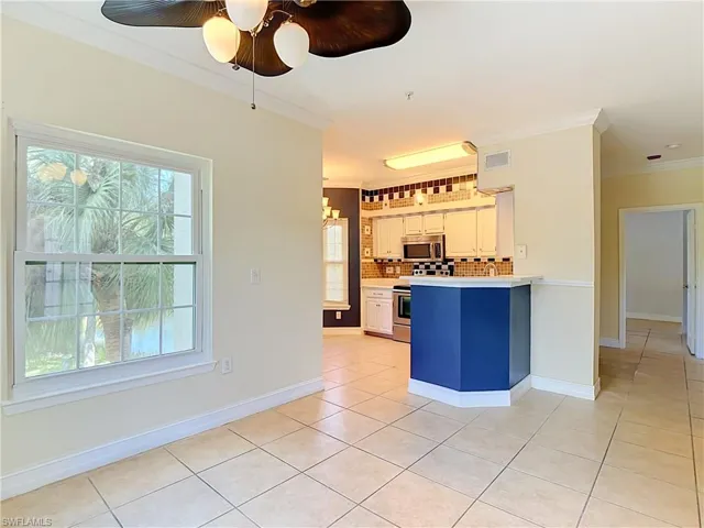 Kitchen featuring white cabinetry, a blue-painted peninsula, tile flooring, stainless steel appliances, and tile backsplash