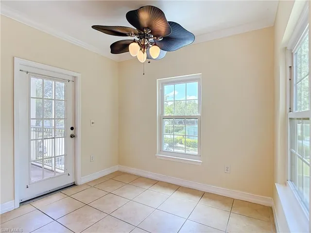 Neutral-toned ceramic tile flooring, multi-pane windows, a full-lite glass entry door, and a sculptural five-blade ceiling fan with integrated lighting