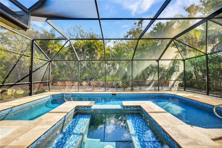 Gorgeous pool and spa surrounded by lush privacy and large screen enclosure.