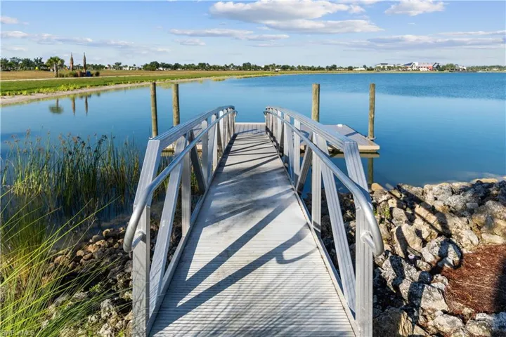Aluminum dock with railing, floating platform, and concrete pilings, situated on a body of water