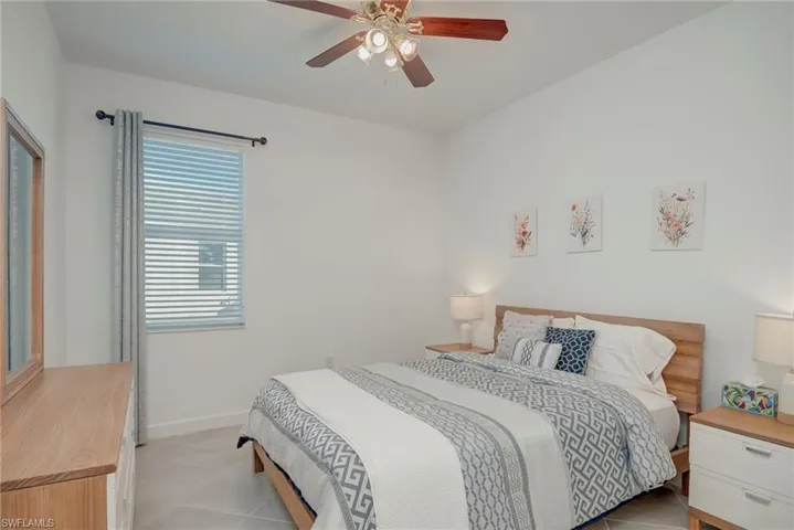 Tiled bedroom featuring a ceiling fan and baseboards