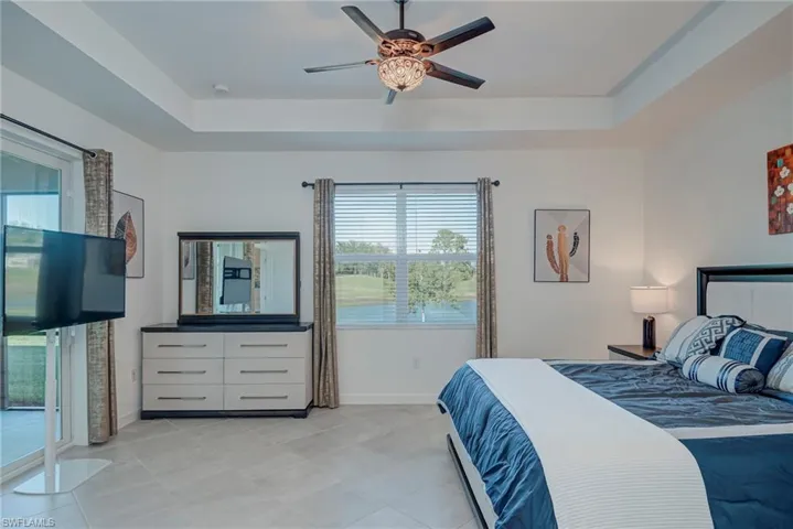 Bedroom featuring a raised ceiling, a ceiling fan, and access to outside