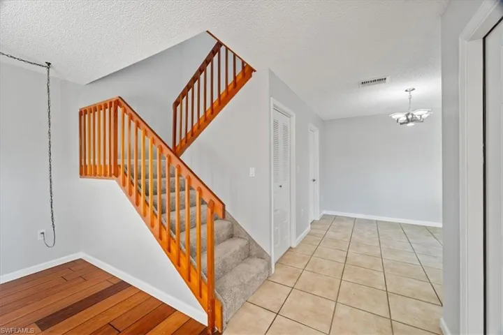 Stairway featuring a chandelier, hardwood / wood-style floors, and a textured ceiling